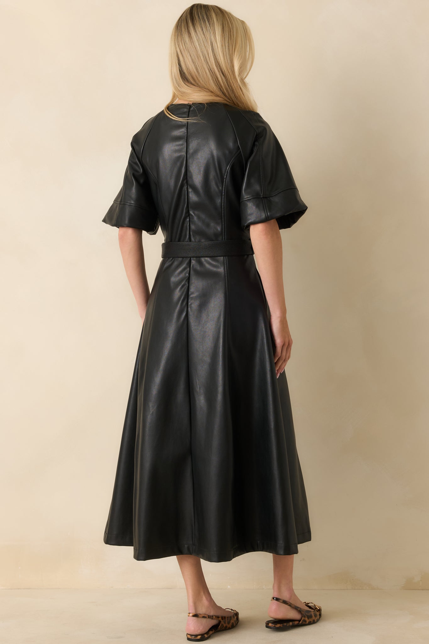 Rear view of the black faux leather midi dress showing clean seaming, concealed zipper, and A-line flow.