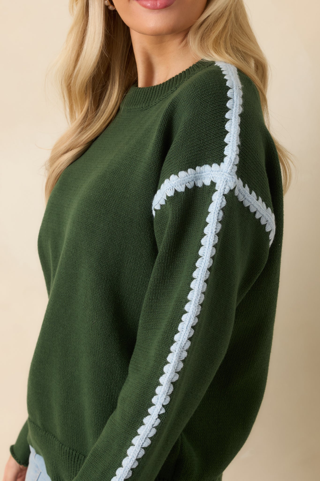 Close-up of ribbed cuffs and blue crochet trim stitched into the sweater’s design.