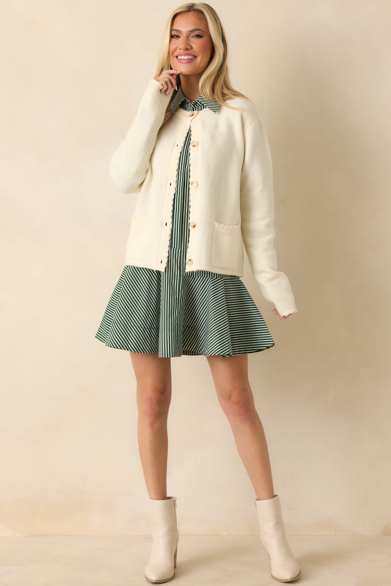 Soft ivory cardigan showcasing scalloped edging along the hem and sleeves with a relaxed, cozy knit feel.