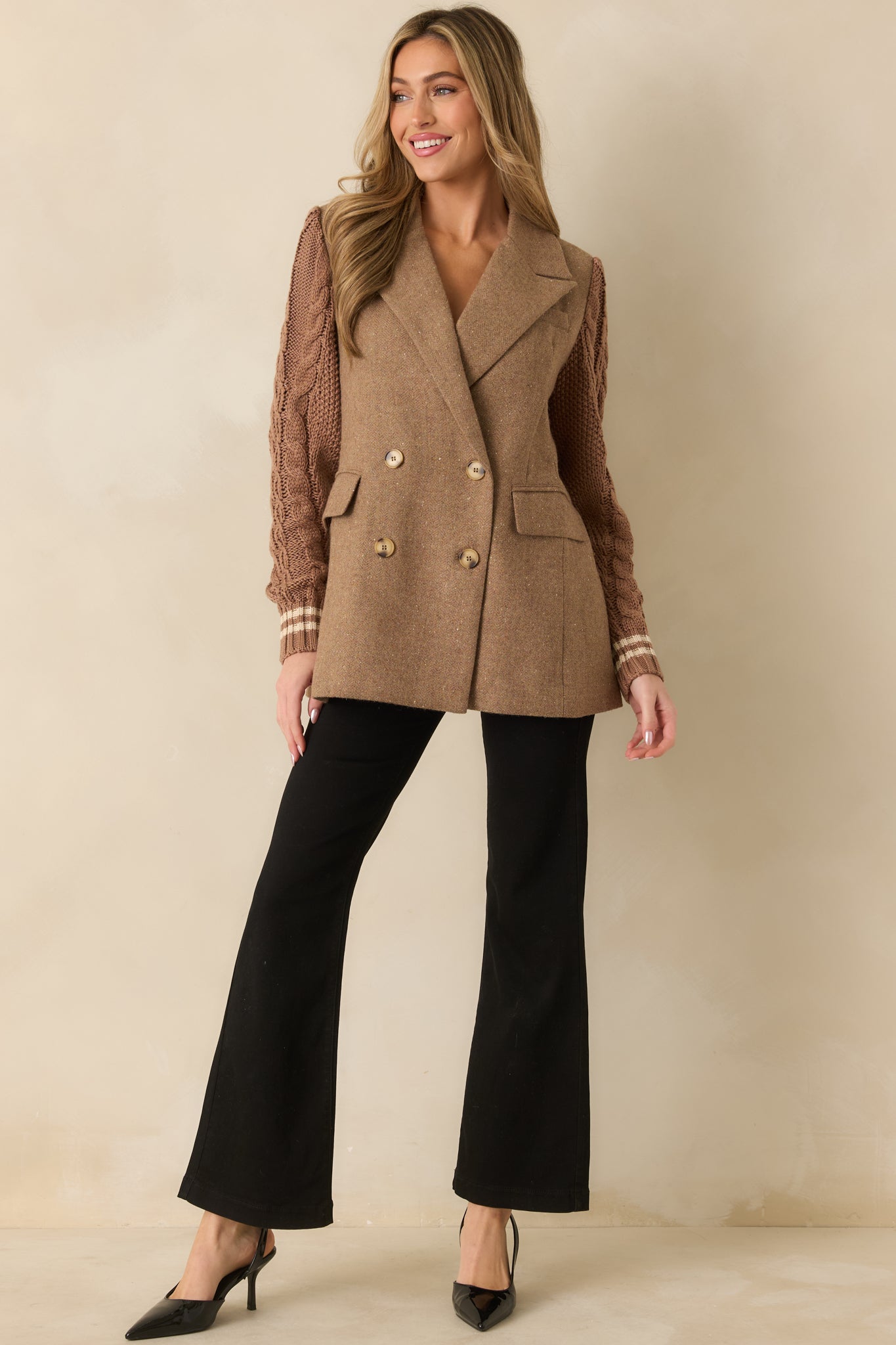 Camel double-breasted blazer displaying a longline silhouette with structured tailoring and knit sleeve contrast.