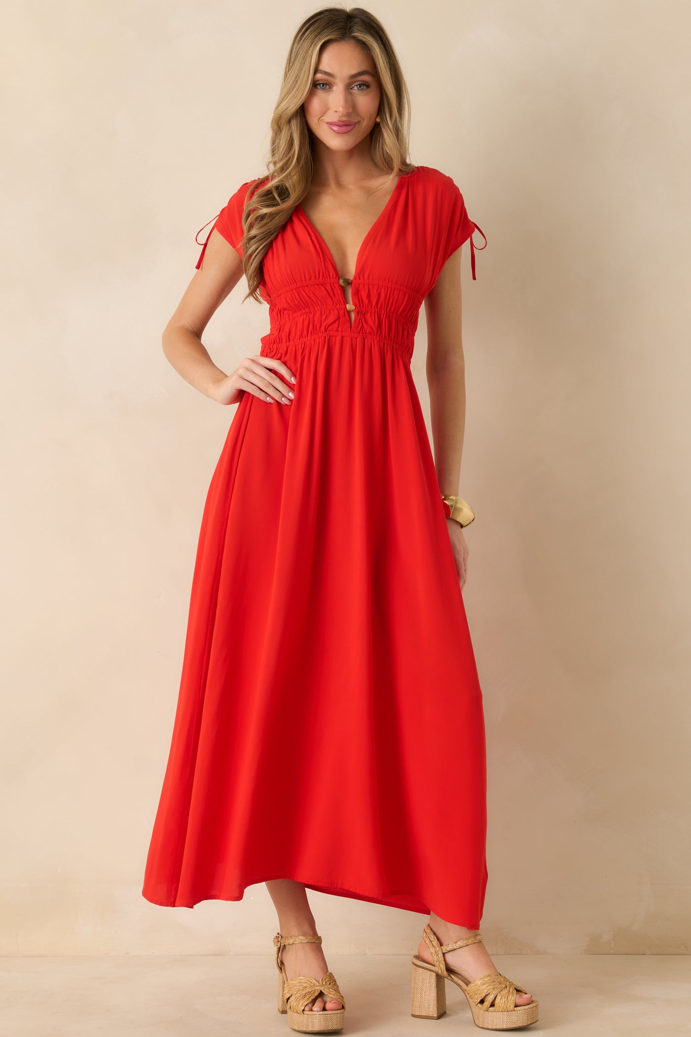 Red midi dress highlighting the draped skirt and adjustable shoulder-tie accents.