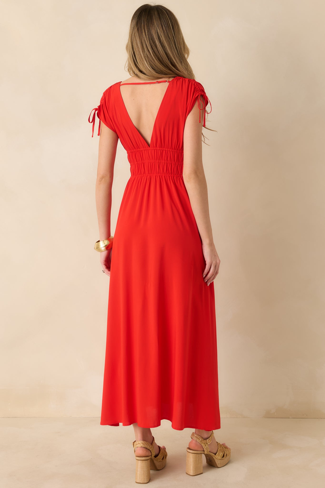 Rear view of the red midi dress featuring the V-back, supportive strap, and draped skirt.