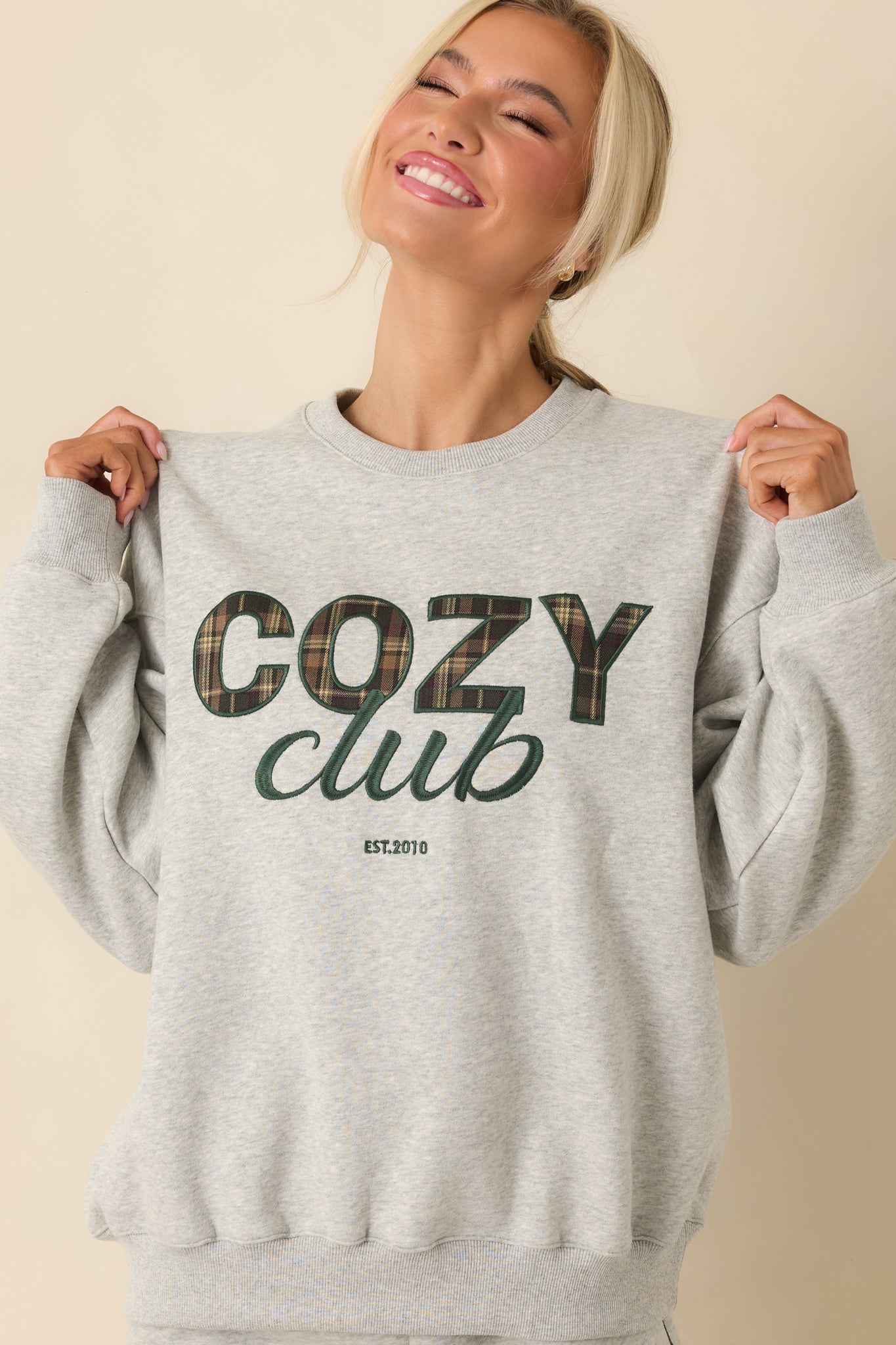 Focused detail of ribbed cuff and embroidered accents on heather grey sweatshirt.