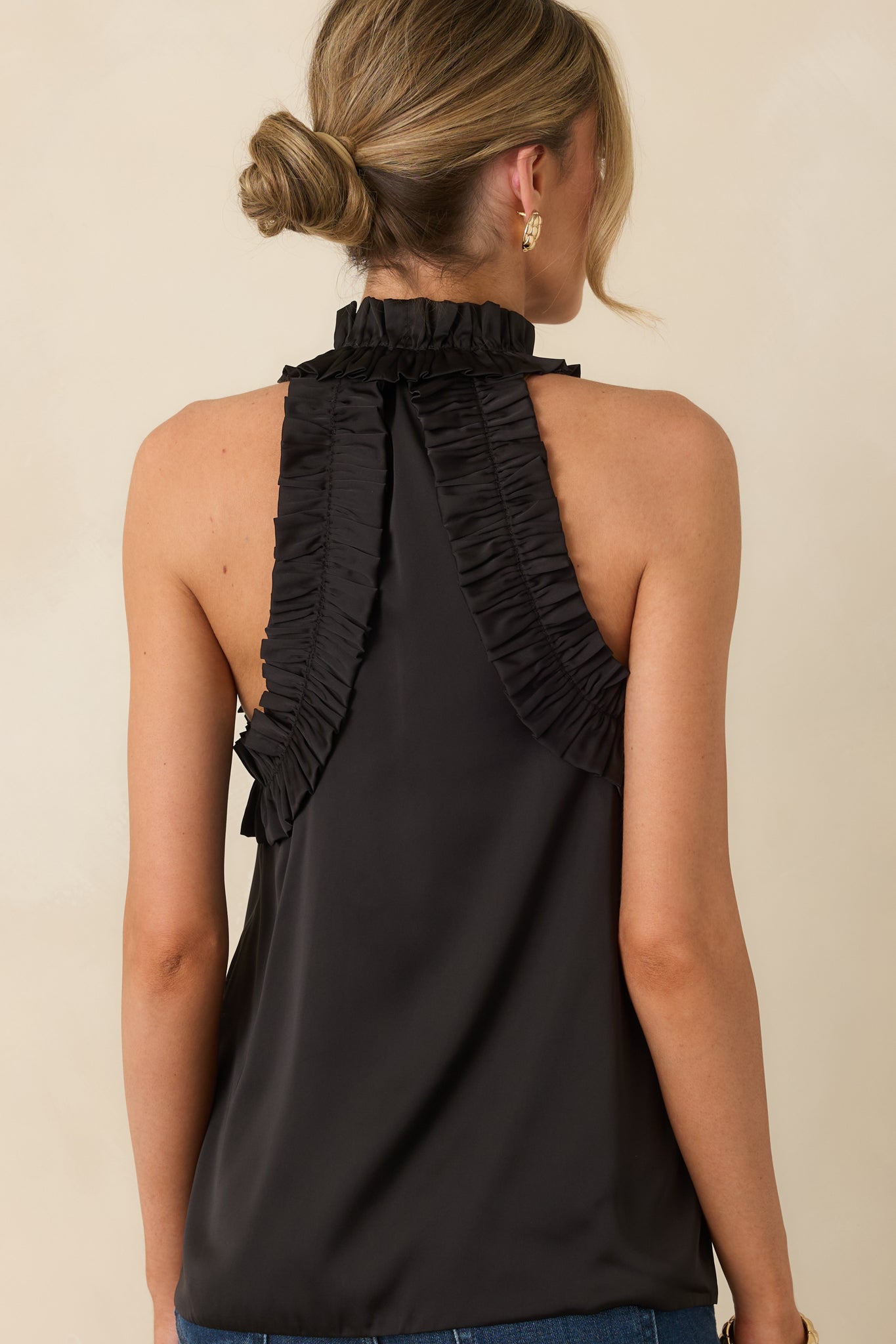 Rear view of the black top showing the clean back finish, lightweight drape, and ruffled collar.