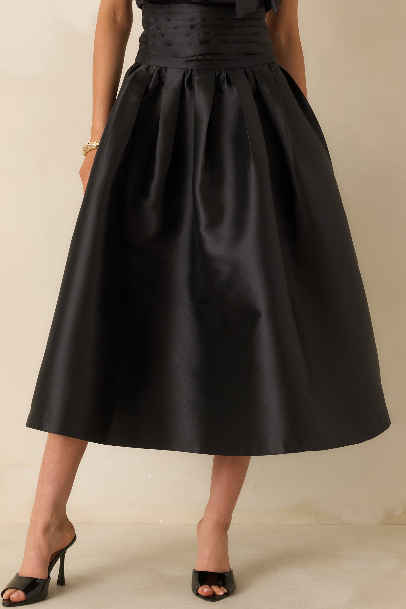 Black maxi skirt with a wide structured waistband and full A-line silhouette featuring pleated volume.