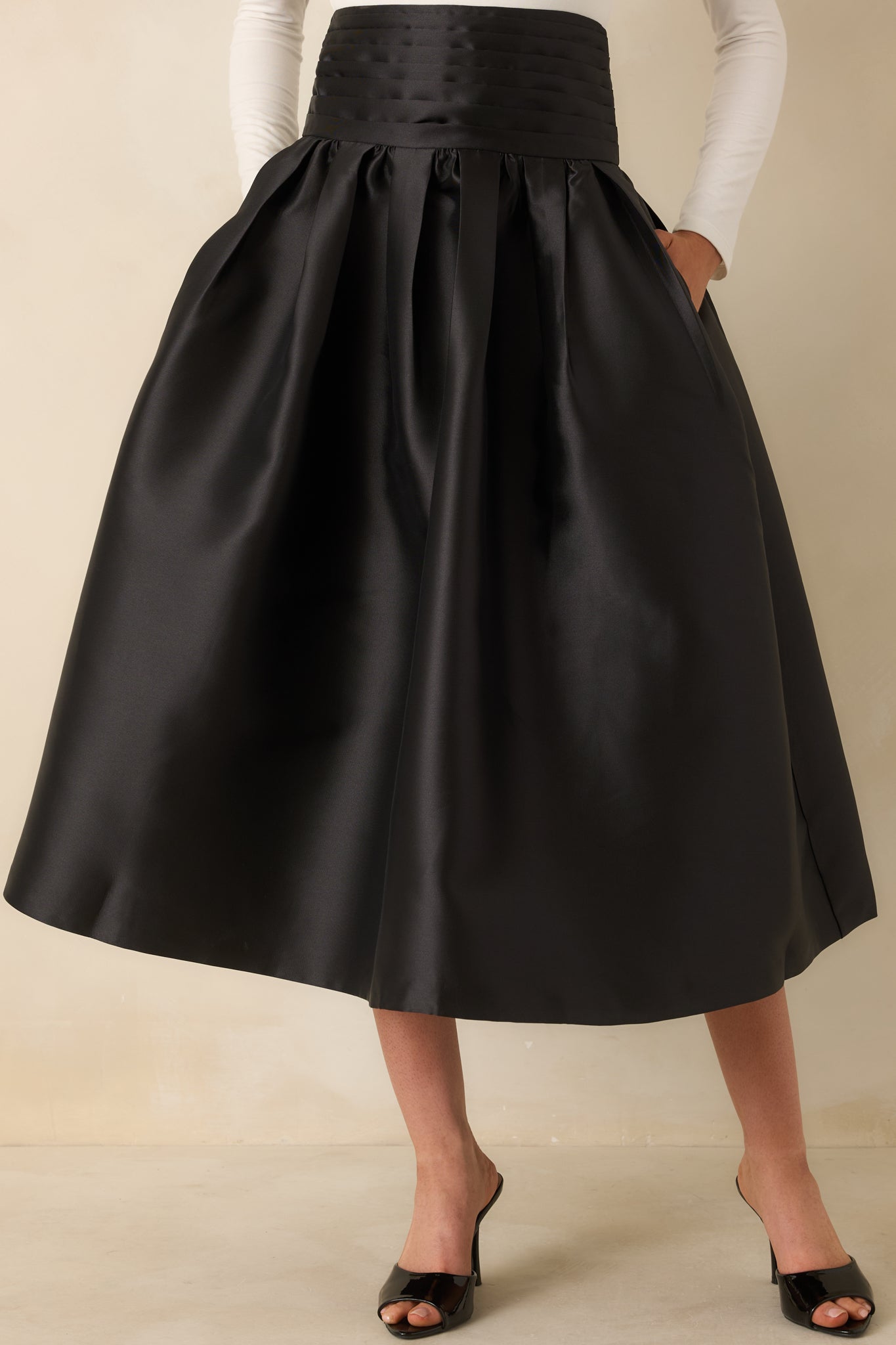 Cropped front view of the black skirt emphasizing the pleated volume and structured waistband.