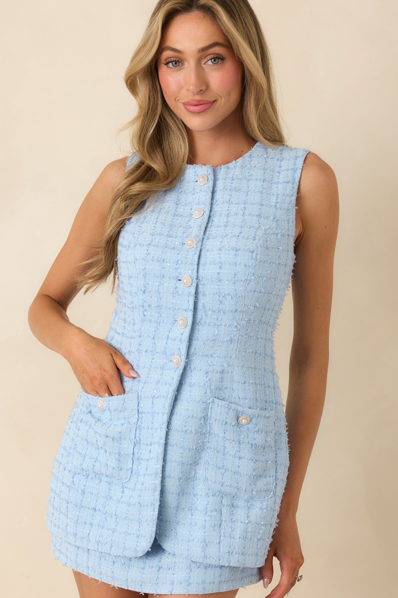 Mini skirt hem and waist seam on blue jacket-style dress with smooth woven finish.