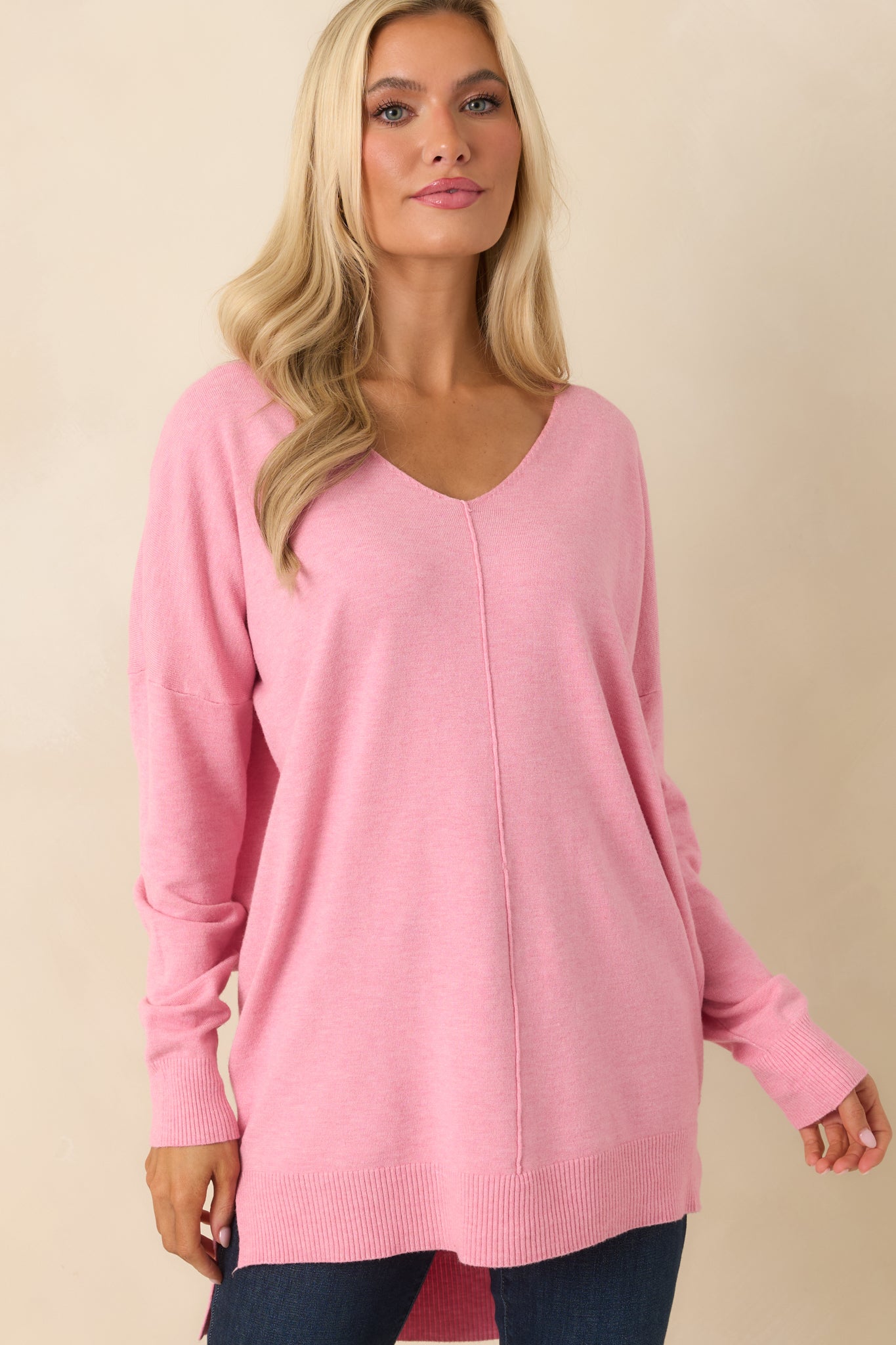 Cropped view emphasizing the bubblegum pink knit pattern and the side slit opening in the longline hem.