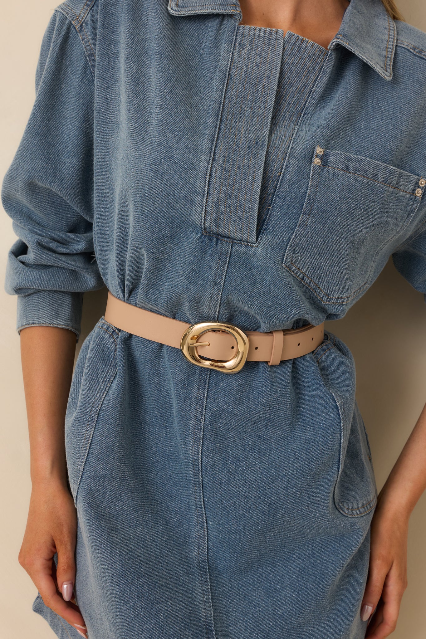 Front-facing cropped view of taupe faux leather belt with gold organic-shaped buckle.