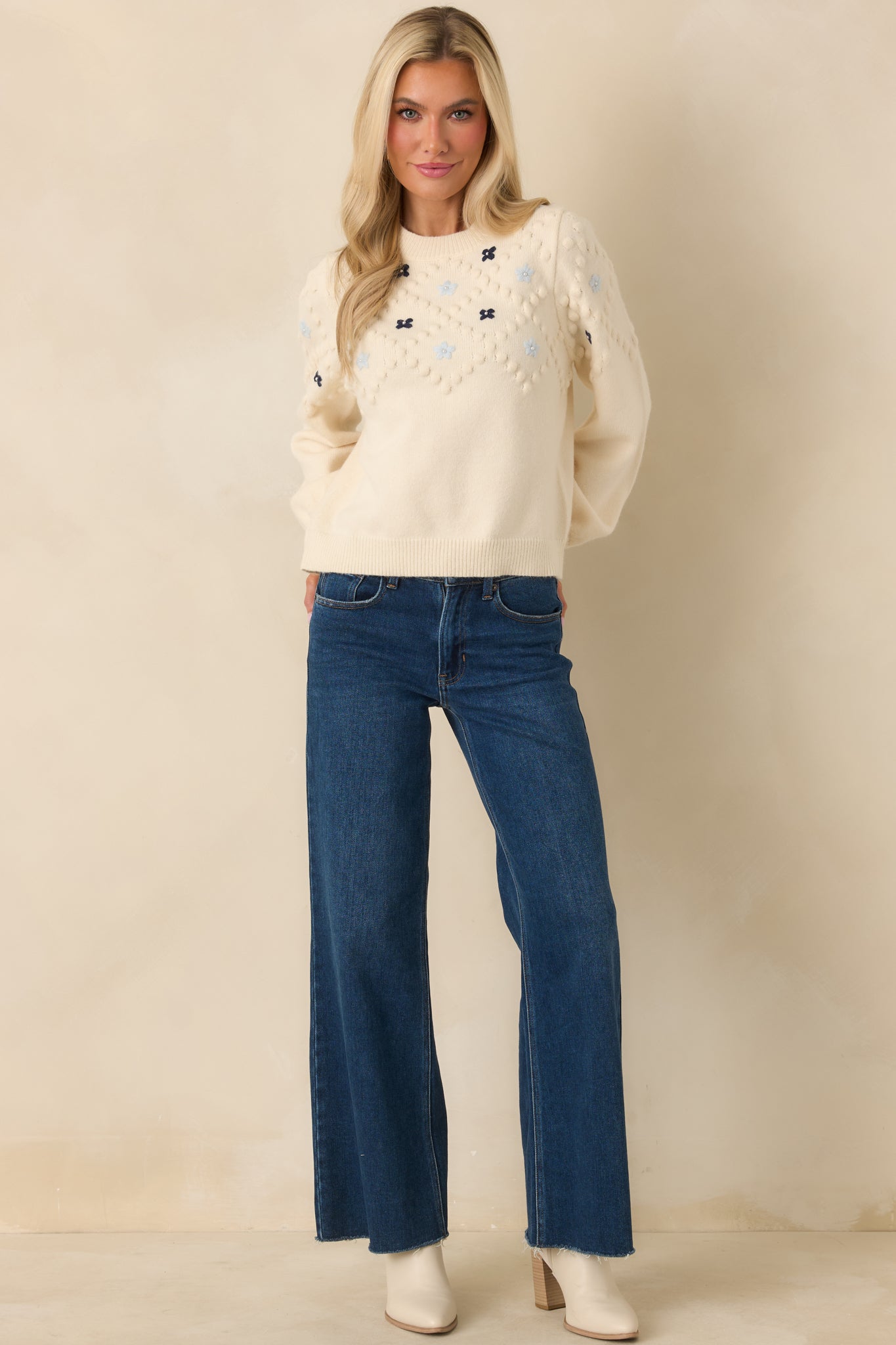 Ivory medium-weight knit sweater with embroidered floral accents, long sleeves, and ribbed neckline, cuffs, and hem.