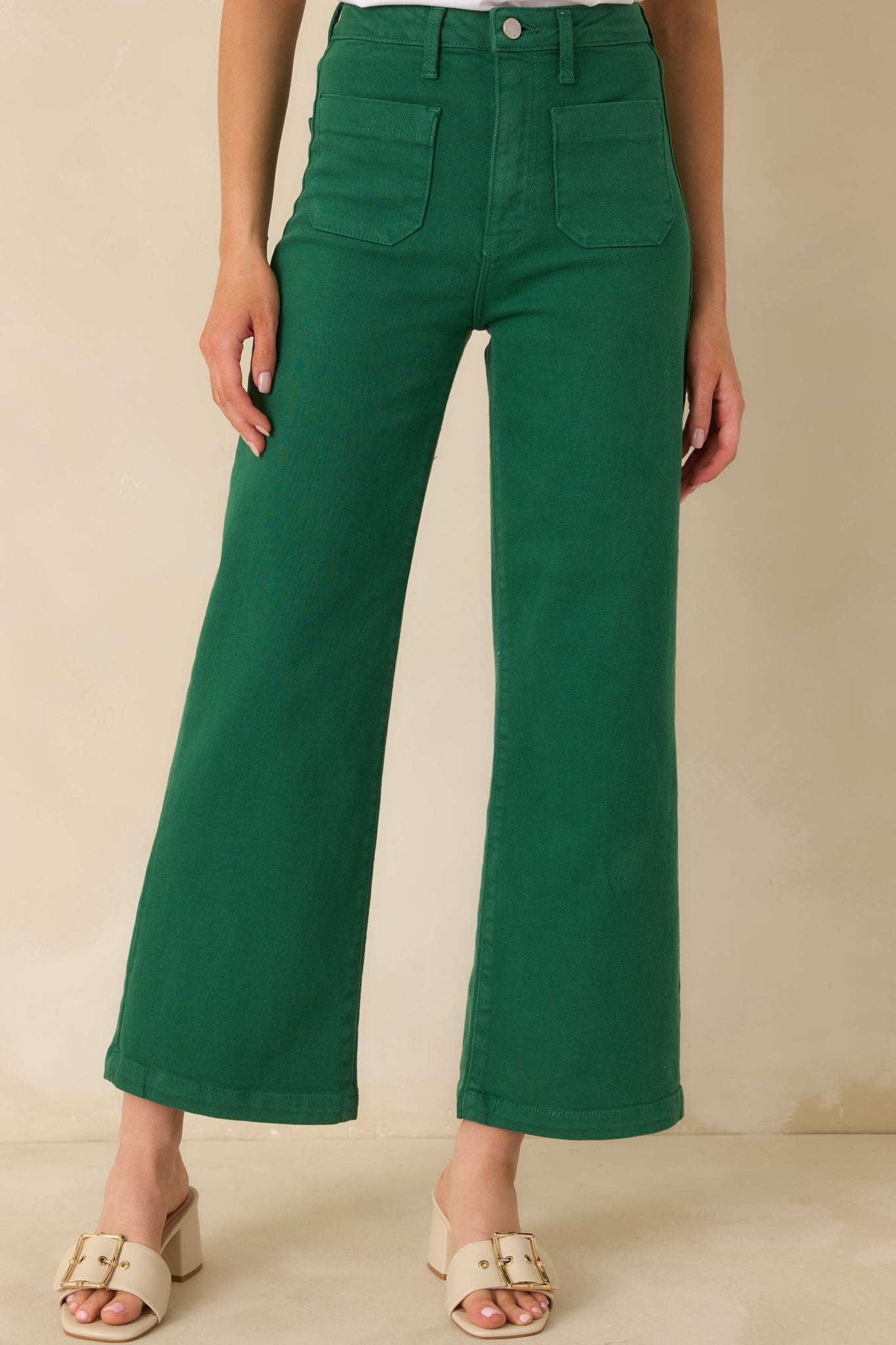 High-rise waistband detail in green denim with sturdy belt loops and a single button closure.