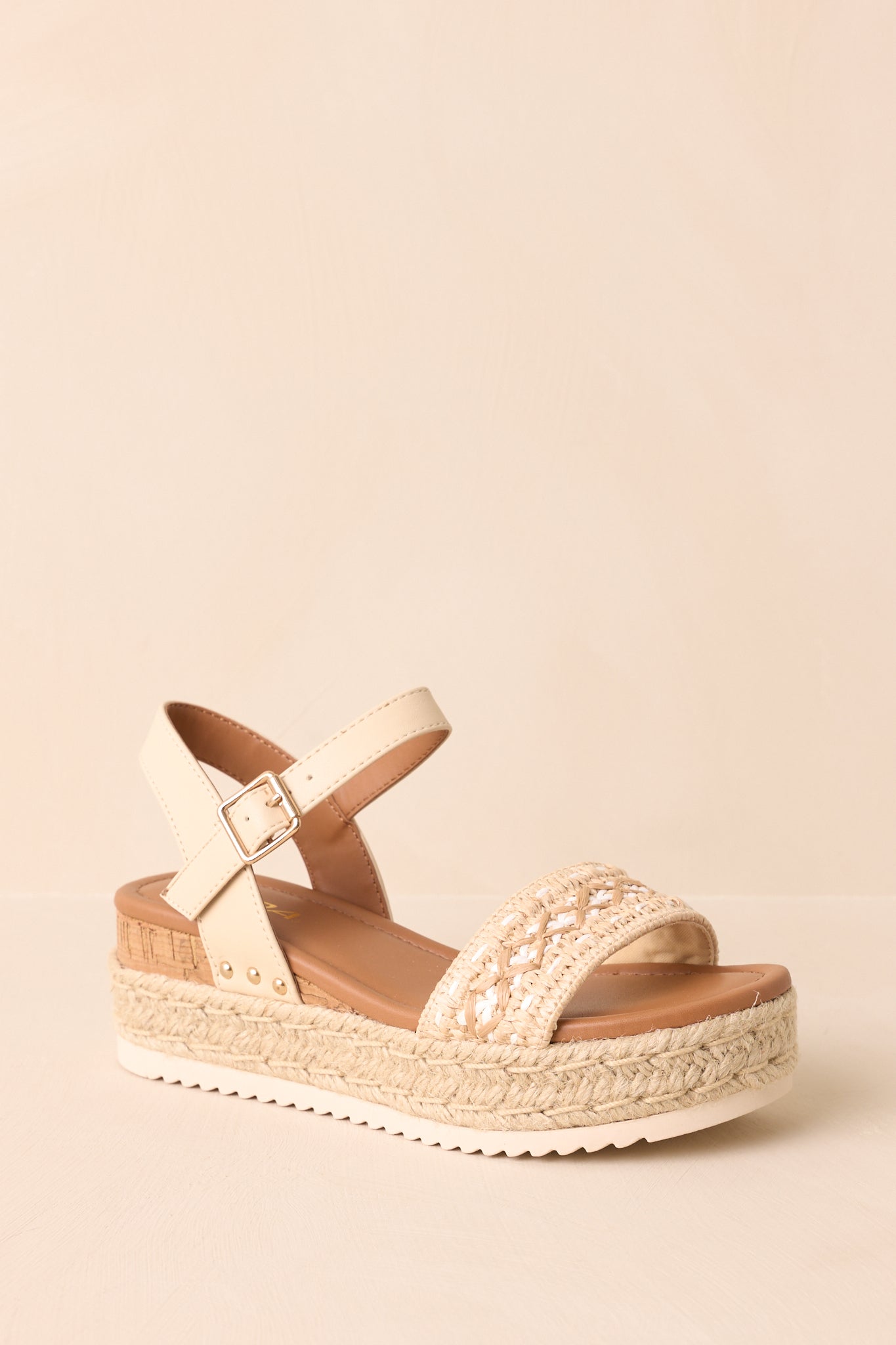 Angled cropped shot emphasizing the woven raffia texture and cork wedge insert.