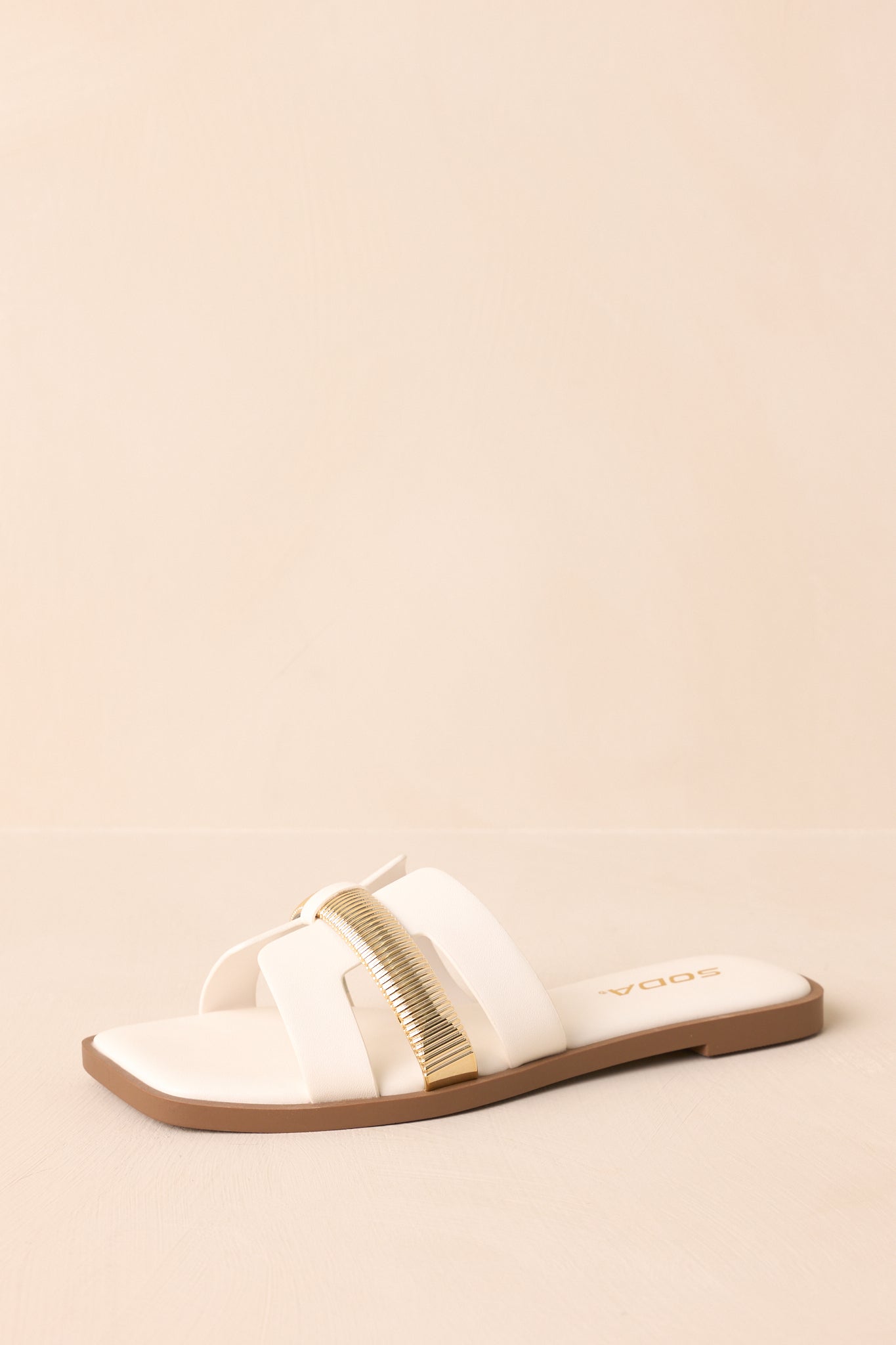 Angled shot showing the footbed and overall structure of the white sandals.