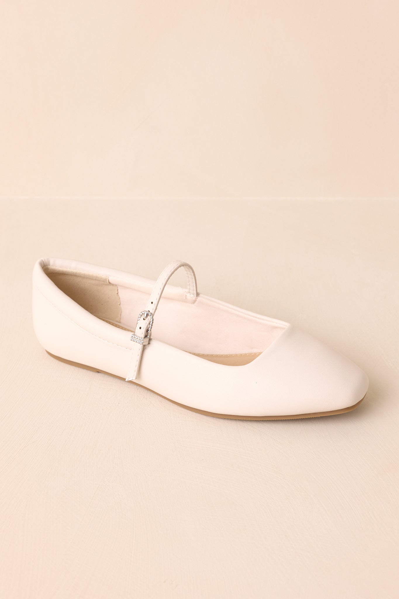 A close top-down perspective of the ivory flats, showing footbed shape and strap placement.