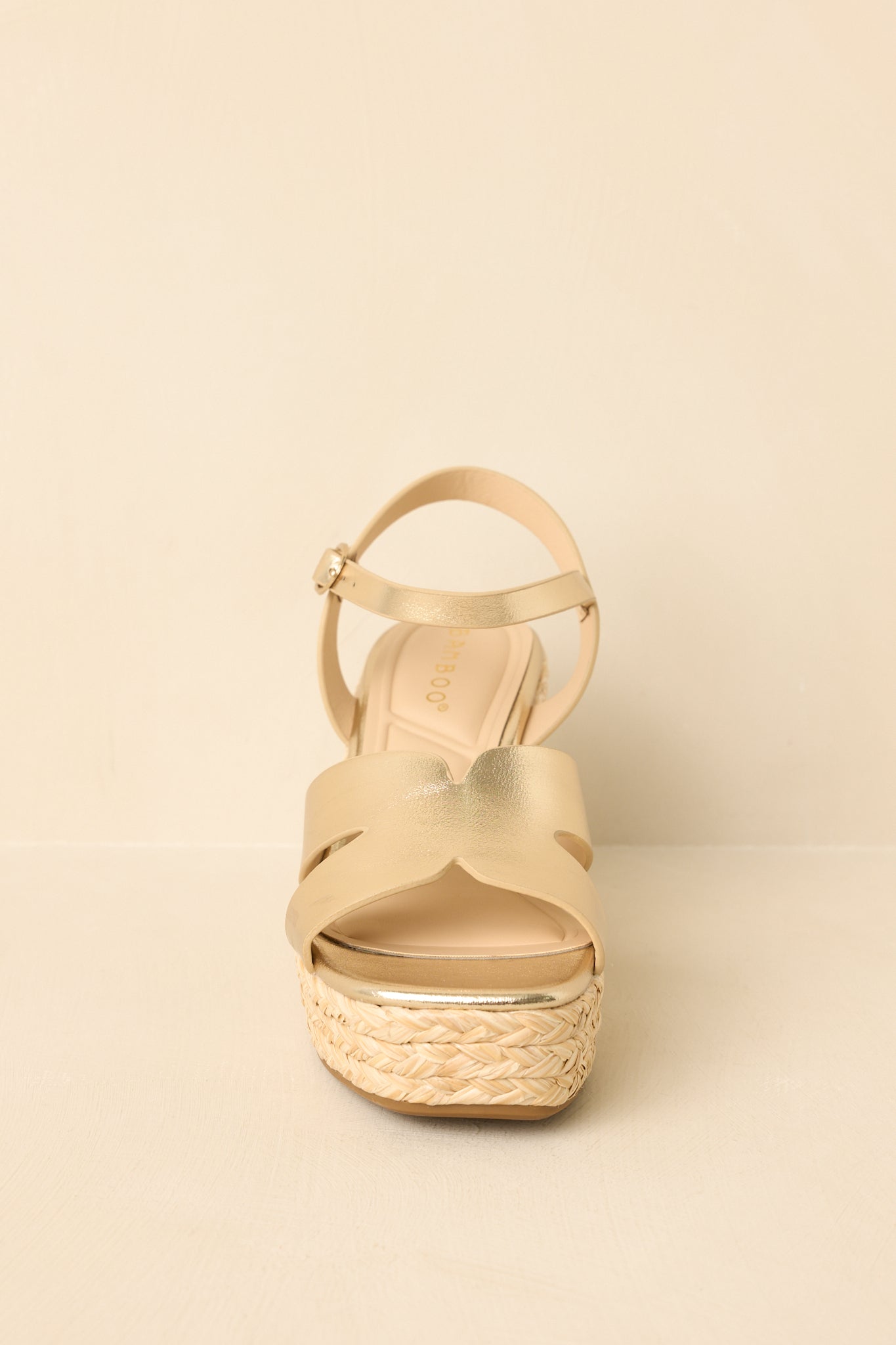 Close cropped angle highlighting gold metallic cut-out straps and the textured espadrille wedge sole.
