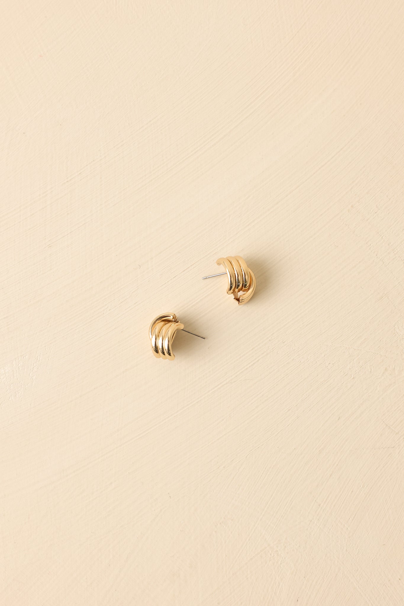 Angled view of knot stud earrings on beige backdrop highlighting polished finish and dimension.