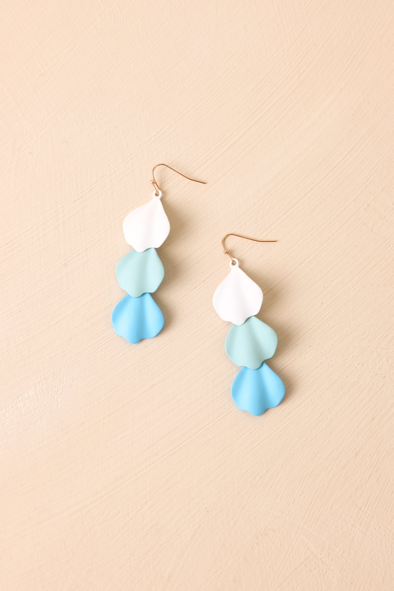 Detailed close-up of blue earrings showcasing layered petal-like elements and smooth sculptural finish.