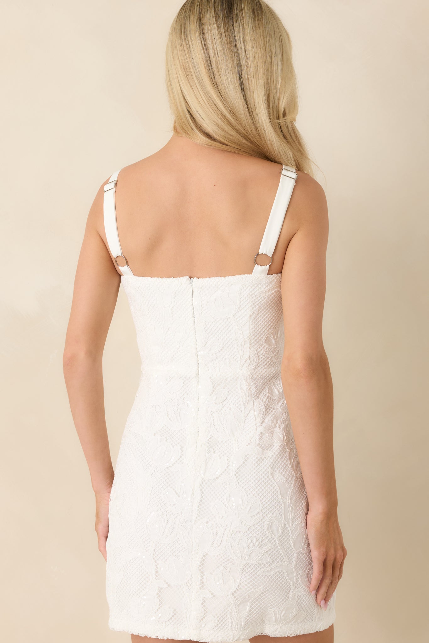 Rear view of lace mini dress with allover lace overlay and structured strap detailing.