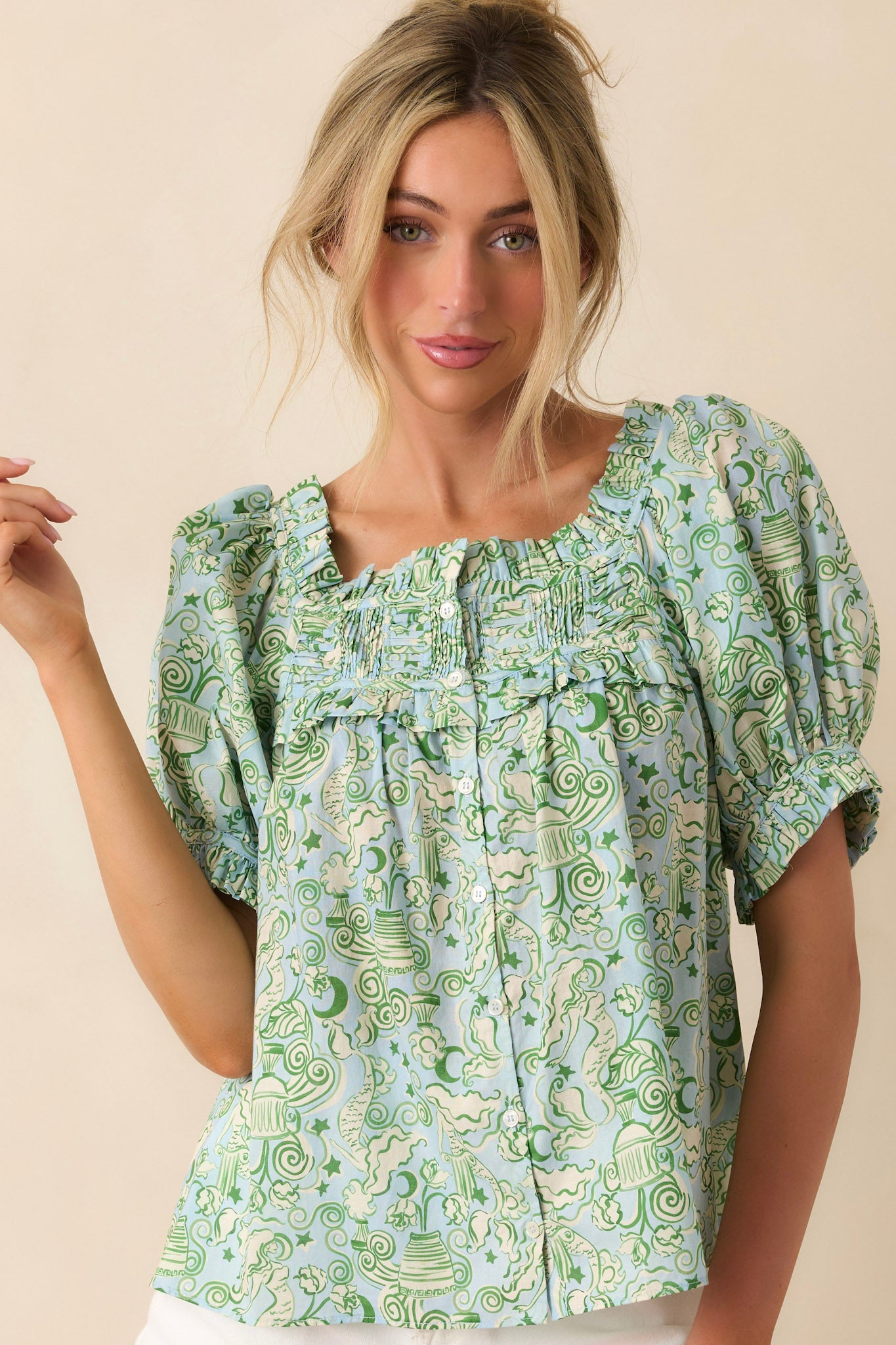 Woman wearing a green patterned blouse against a beige background