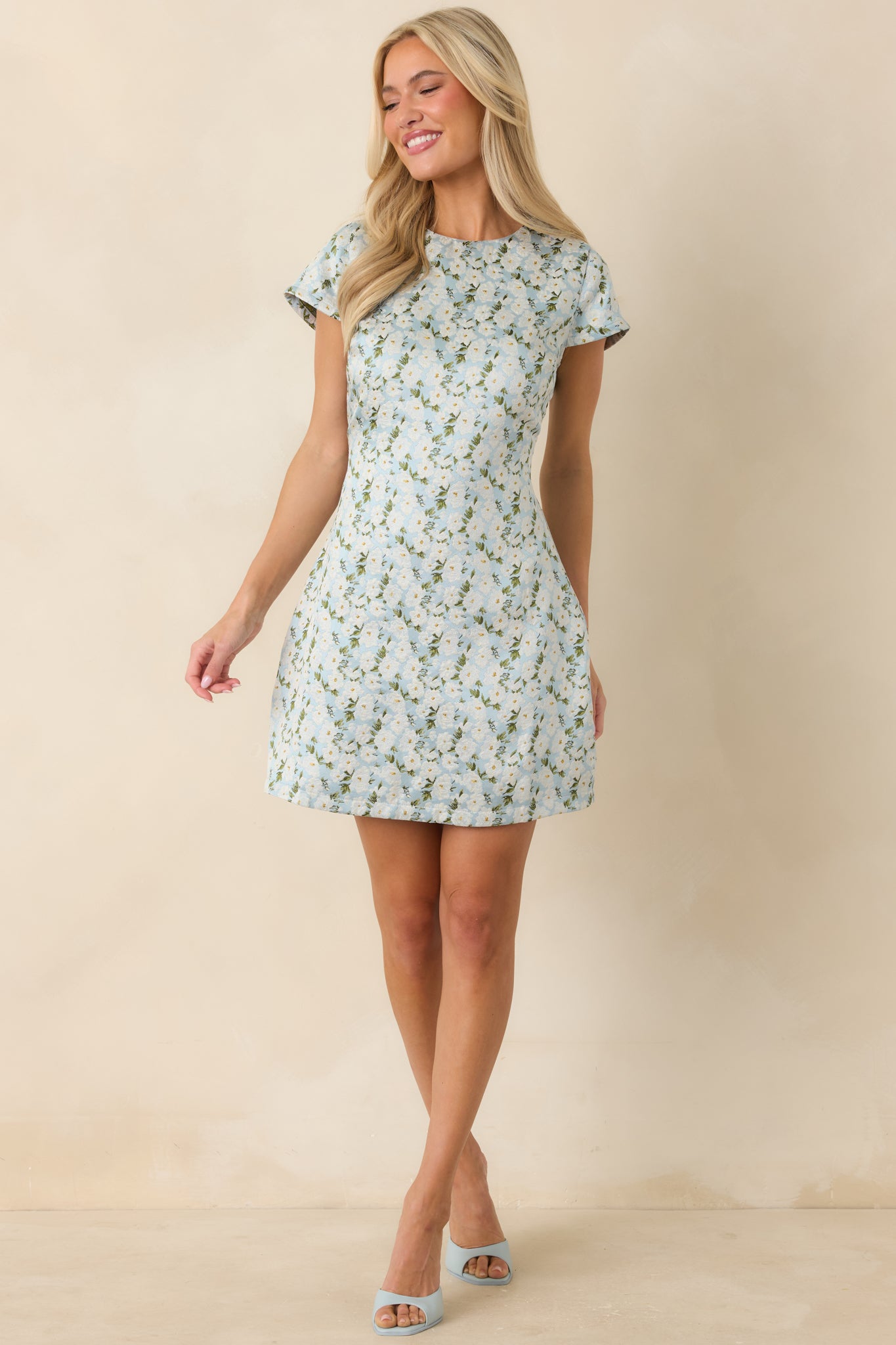 Structured mini dress in light blue and white floral jacquard with cap sleeves and tailored shape.