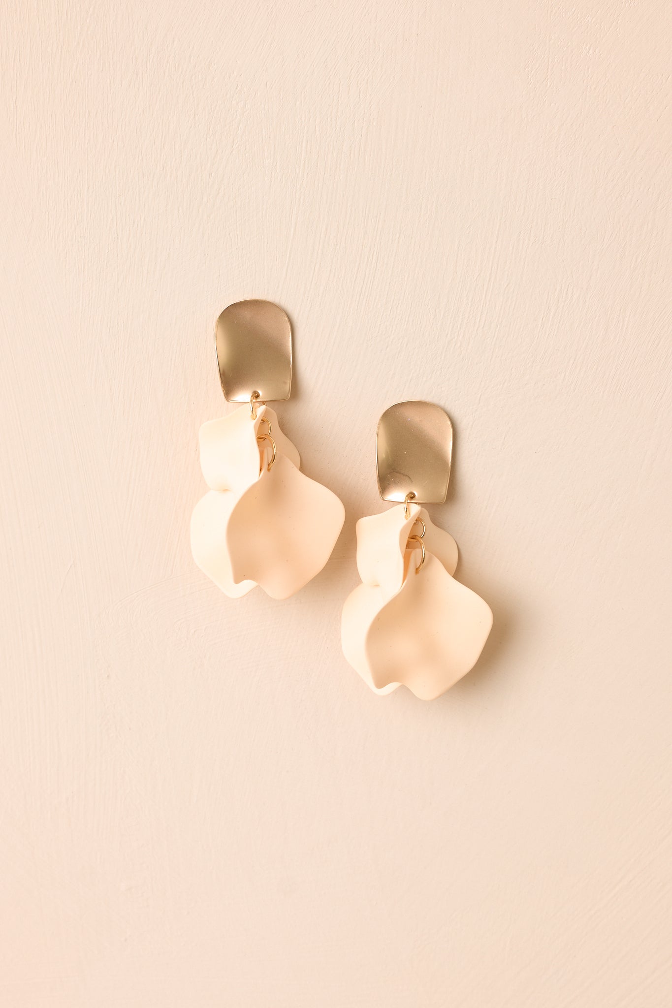 Front view of peach ivory petal earrings displayed on beige background emphasizing cascading layered design.