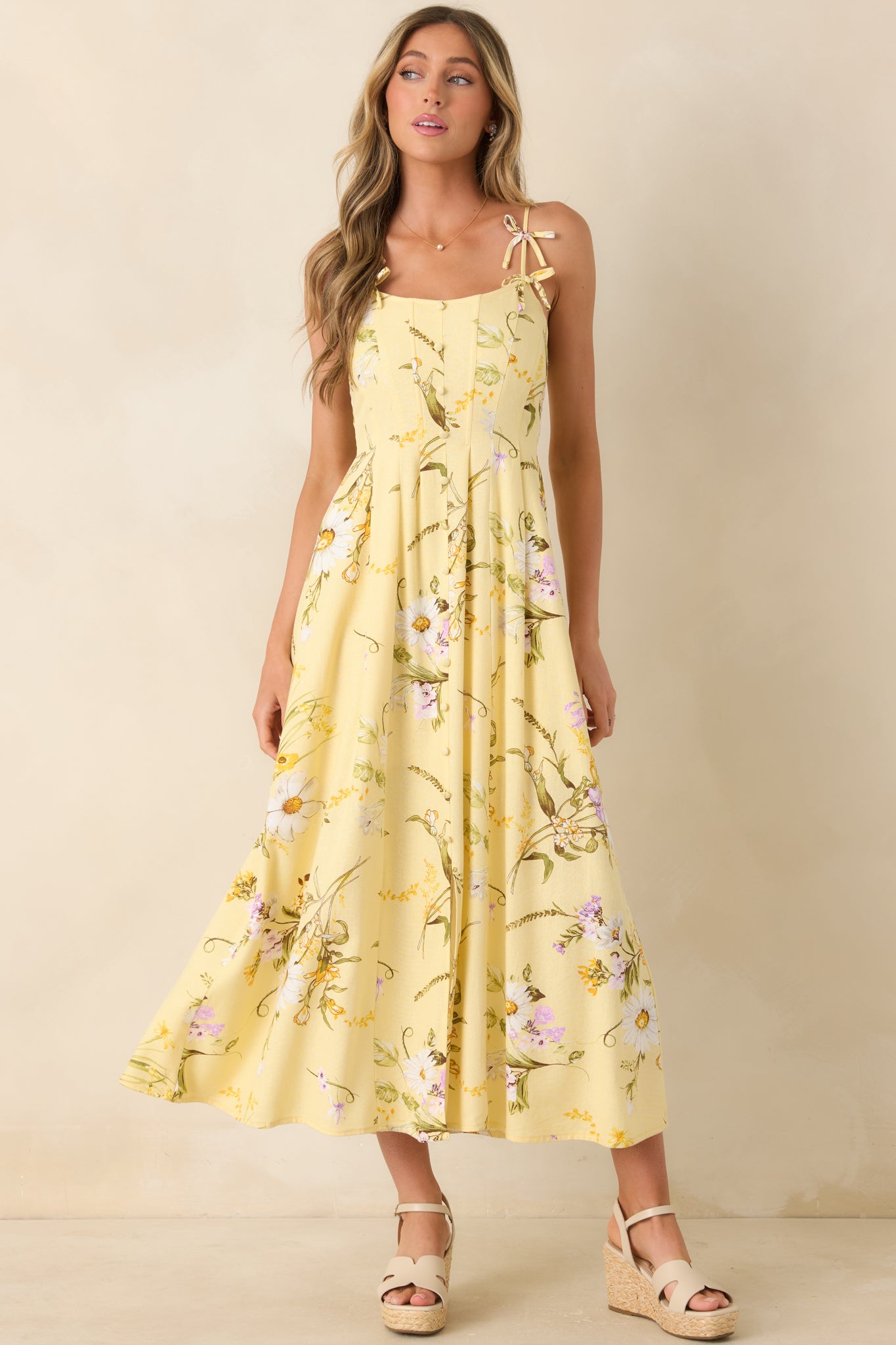 Yellow floral midi dress with bow-accent shoulder straps, paneled bodice shaping, and a soft, flowing linen-blend skirt.