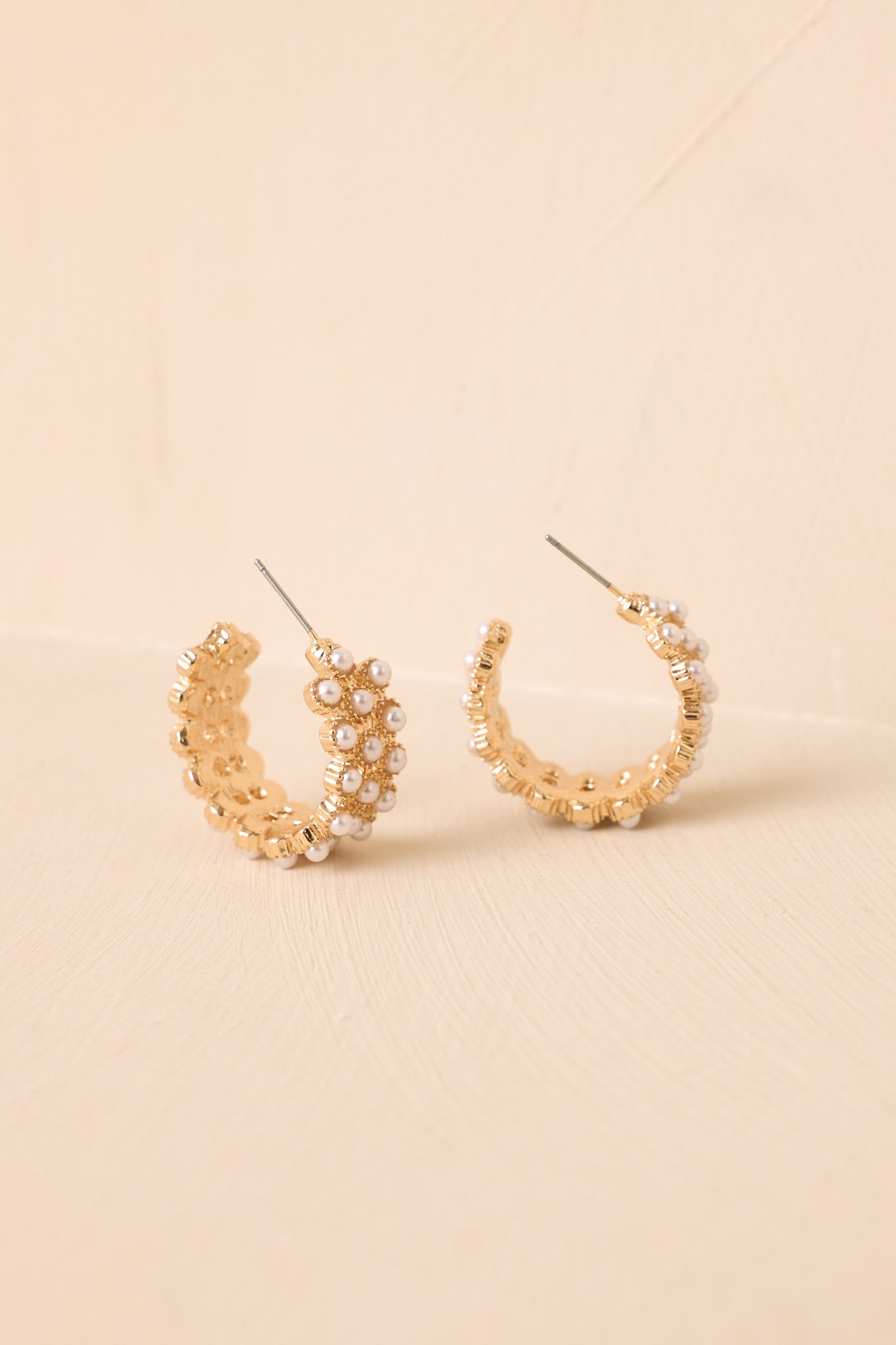 Lightweight gold-tone hoop earrings featuring layered faux pearl accents arranged in neat rows along the curved silhouette.
