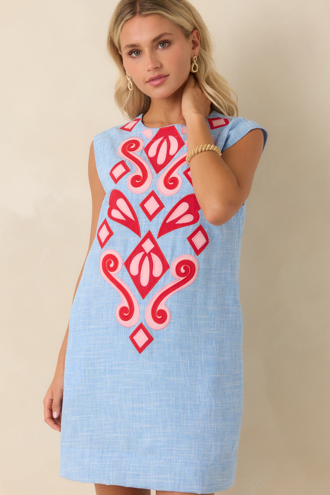 Blue heather mini dress featuring detailed red and pink appliqué embellishments and a high neckline.