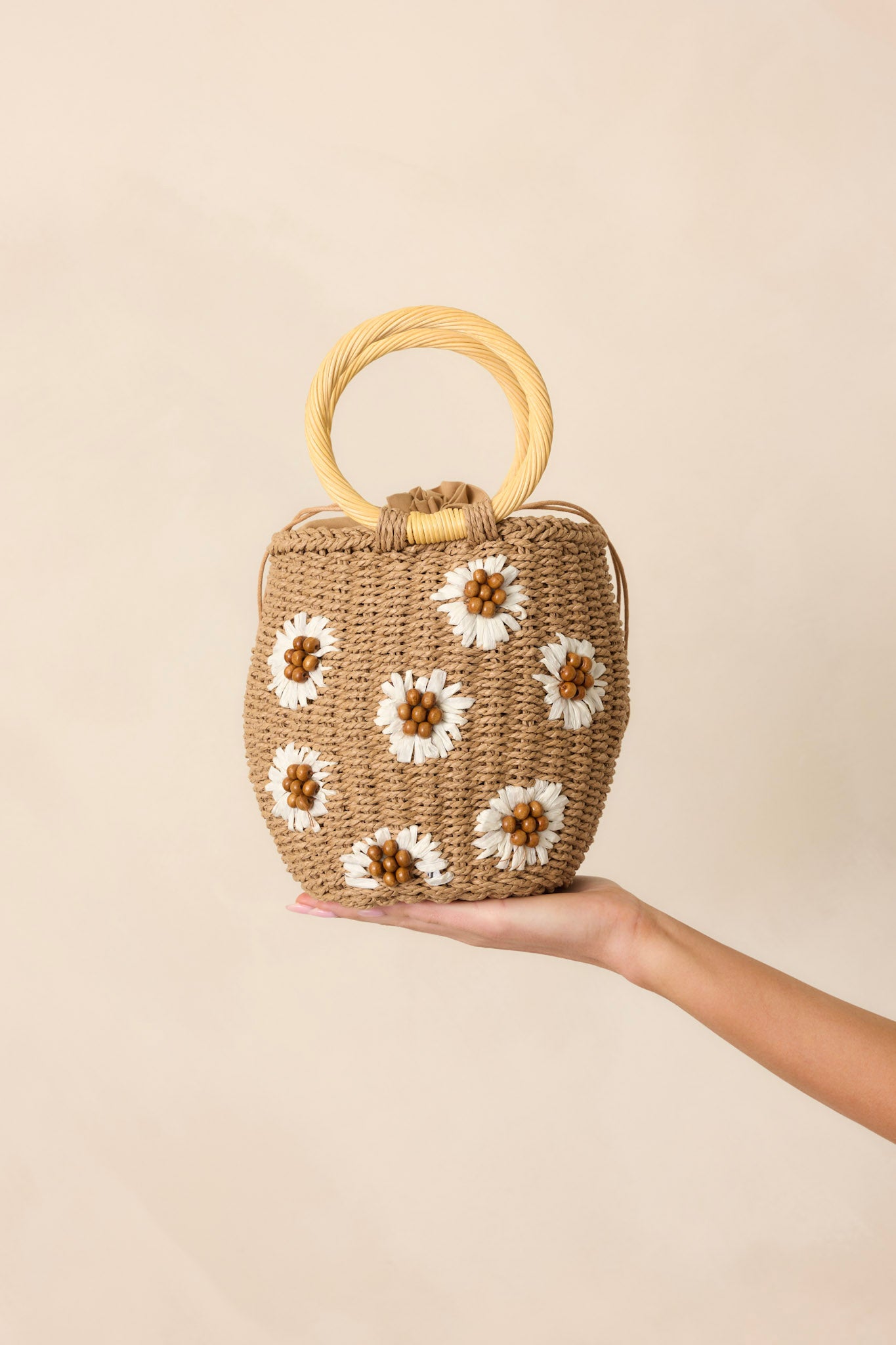 A partial view of the handbag, focusing on the woven straw texture and delicate white straw flowers.