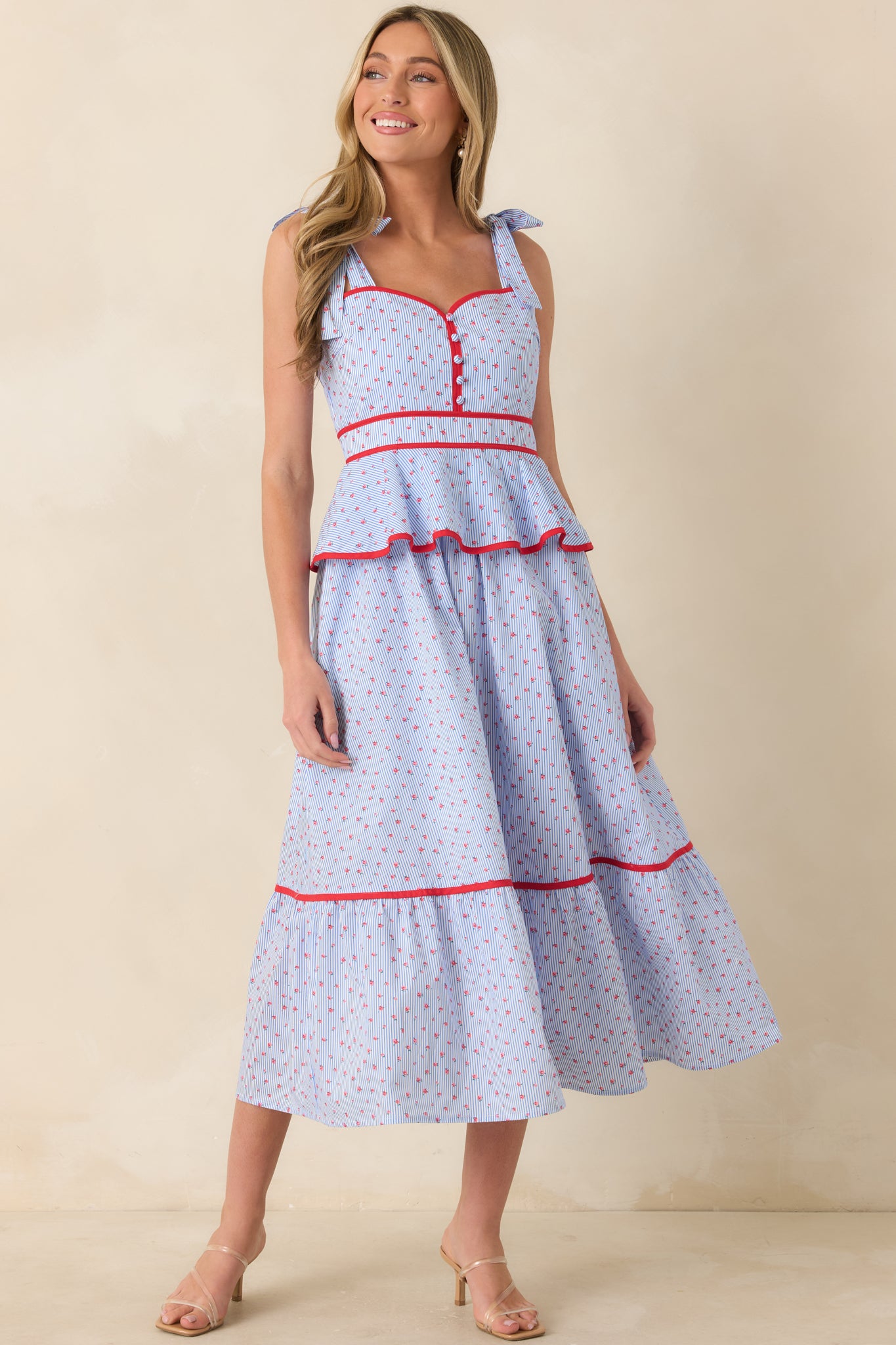 Light blue and red printed midi dress showcasing adjustable straps and softly flared skirt silhouette.