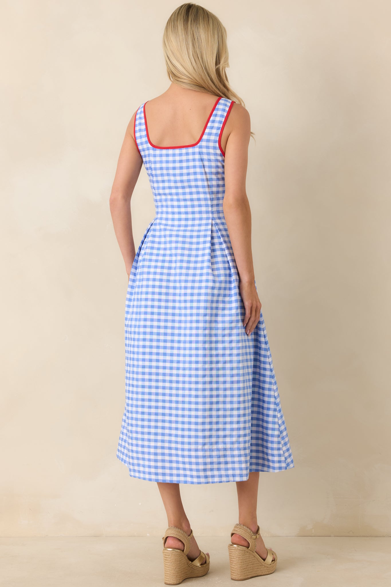 Rear view of blue and white gingham midi dress featuring sleeveless cut and hidden side zipper closure.