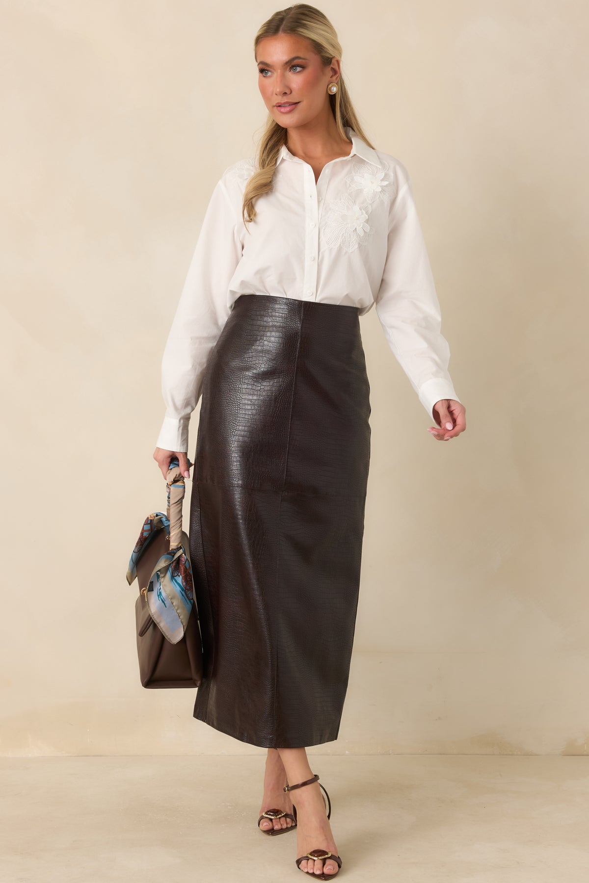 A smooth high waistband and fitted straight cut highlight the polished shape of this espresso crocodile-textured midi skirt.