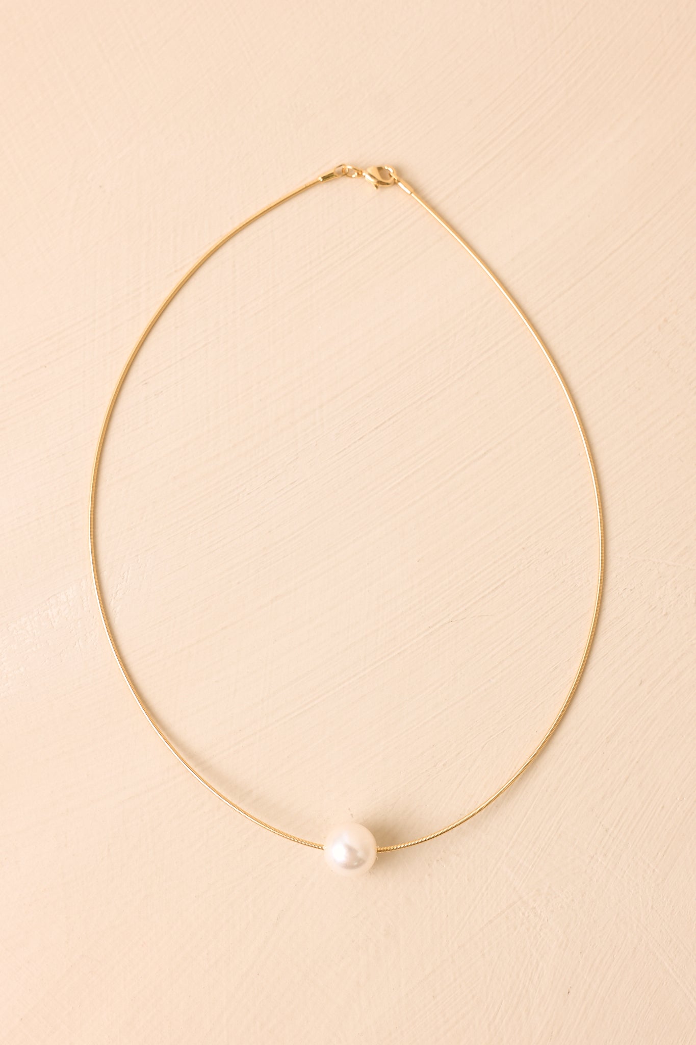 Simple yet elegant necklace with a luminous pearl centerpiece and sleek gold-tone chain for a timeless finish.