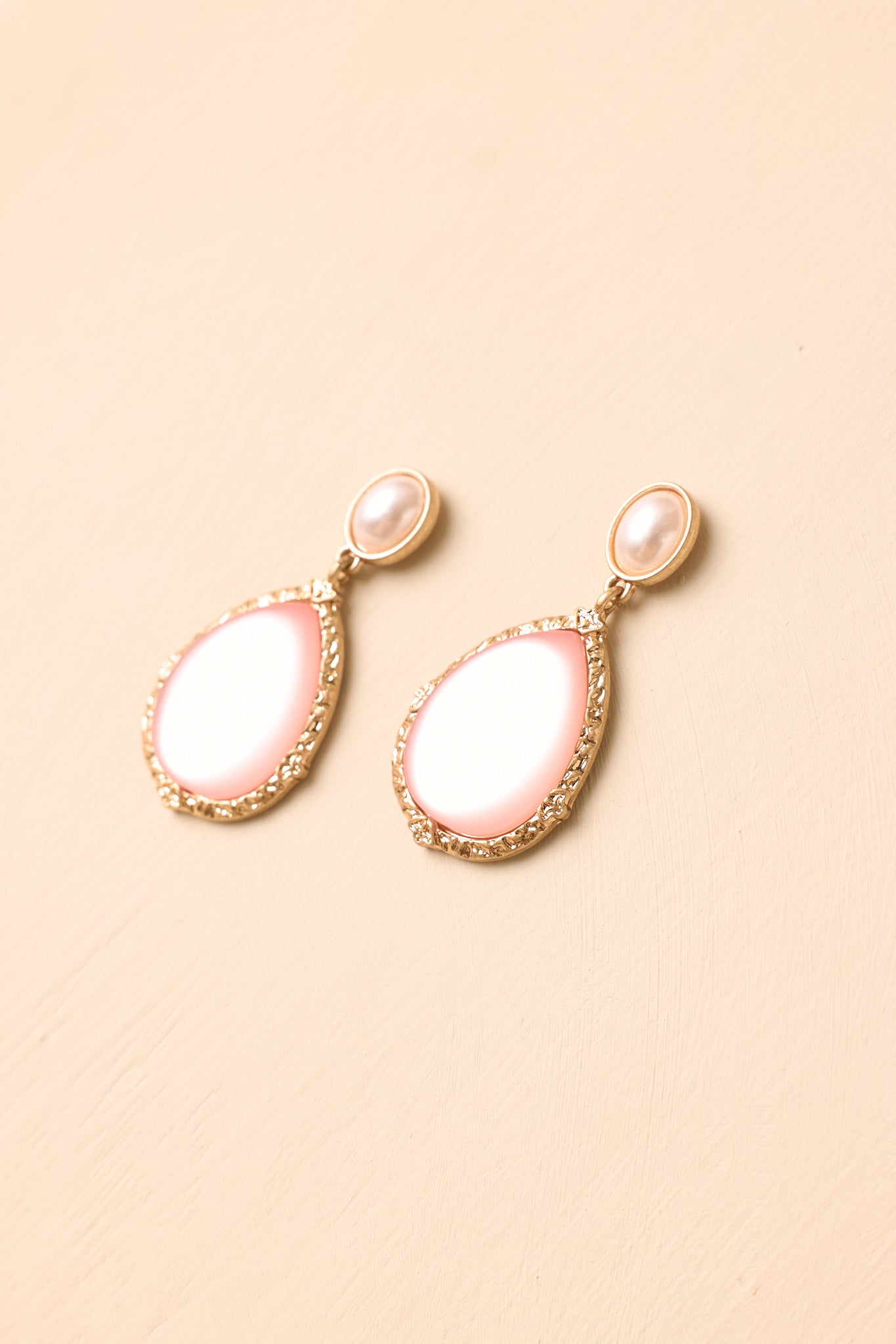 Pearl-inspired drop earrings showcasing soft pink tones, sculpted gold detailing, and a timeless elegant design.