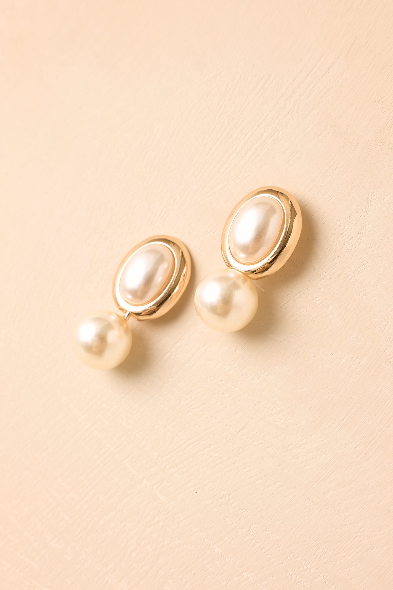 Gold-tone earrings with pearlescent details showcasing a classic drop design and polished metallic finish.