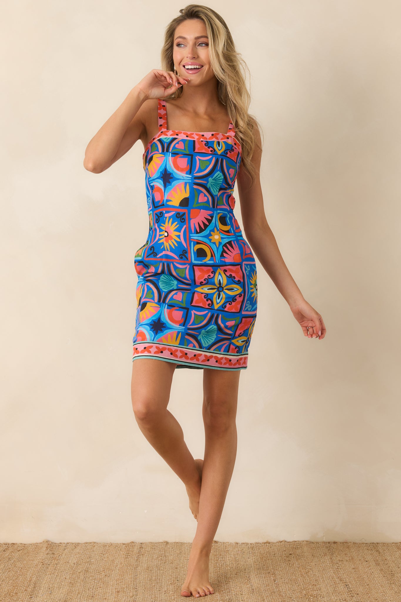 Blue printed mini dress with a structured square neckline, side pockets, and decorative contrast trim details.