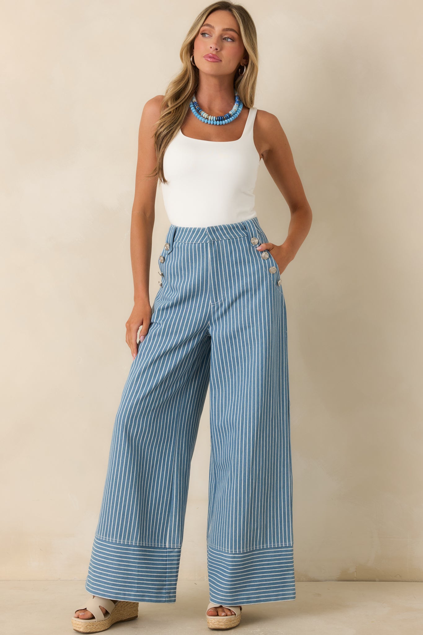 Blue striped wide leg pants featuring a high-rise fit, structured cotton blend fabric, and sailor-style silver button detailing.