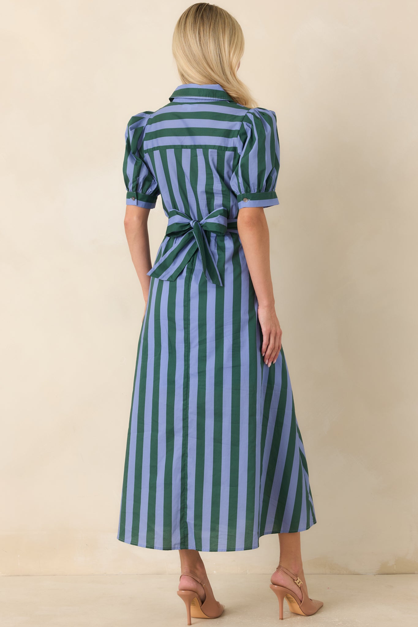 Rear view of the blue and green striped midi dress featuring the wide wrap-style sash tied into a bow, softly puffed sleeves, and the full skirt with a smooth, flowing silhouette.