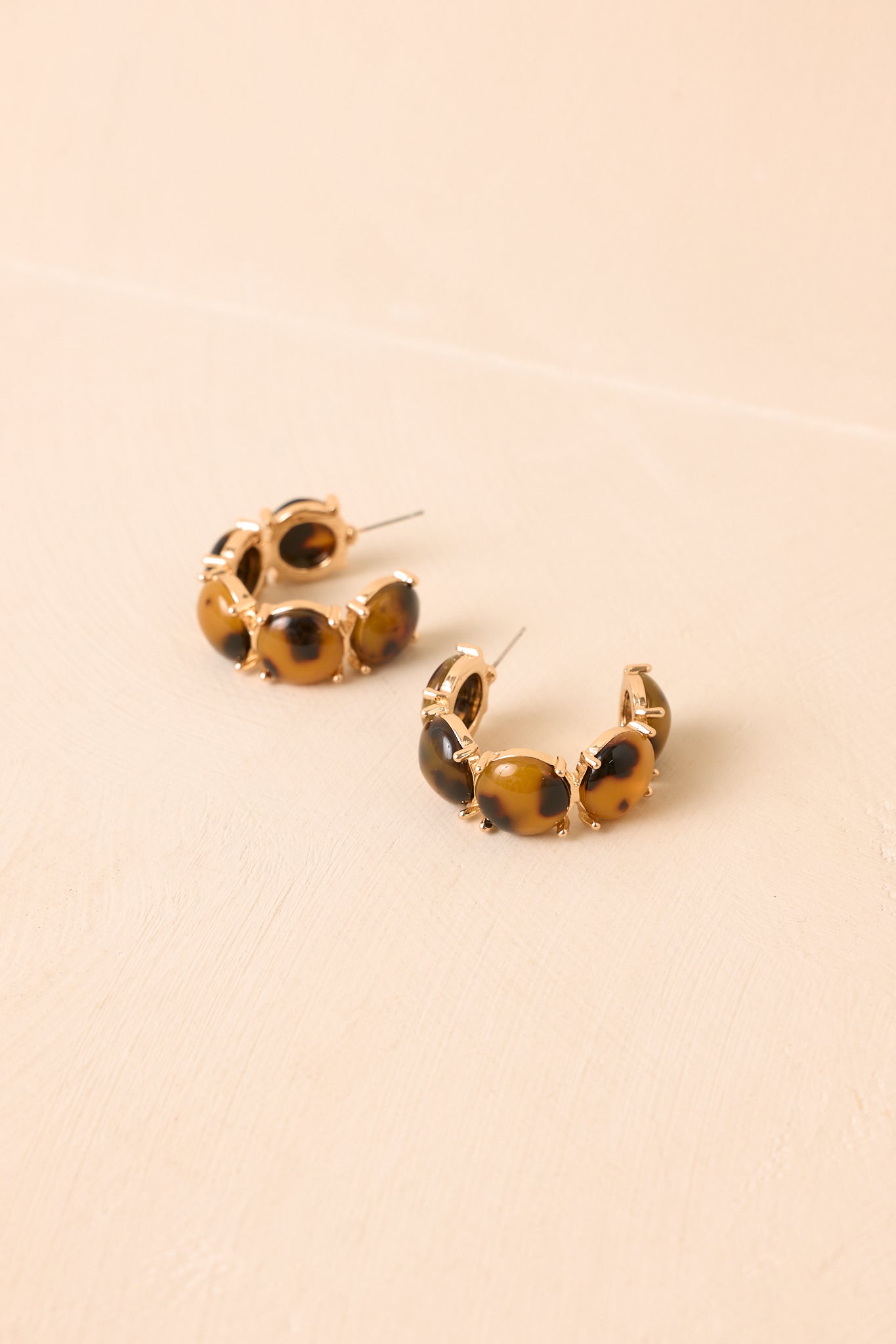 Gold-tone hoop earrings featuring glossy tortoise acetate accents in an open silhouette with a polished finish.