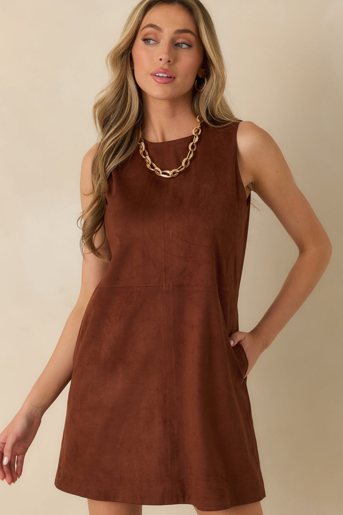 Functional side pockets blend into the clean silhouette of the brown faux suede mini dress.