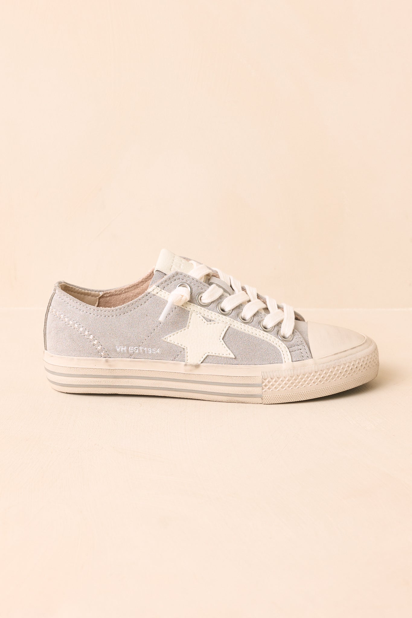 Close view of the dusty blue suede sneakers emphasizing the signature suede star, perforated side panels, contrasting woven laces, and soft suede texture.