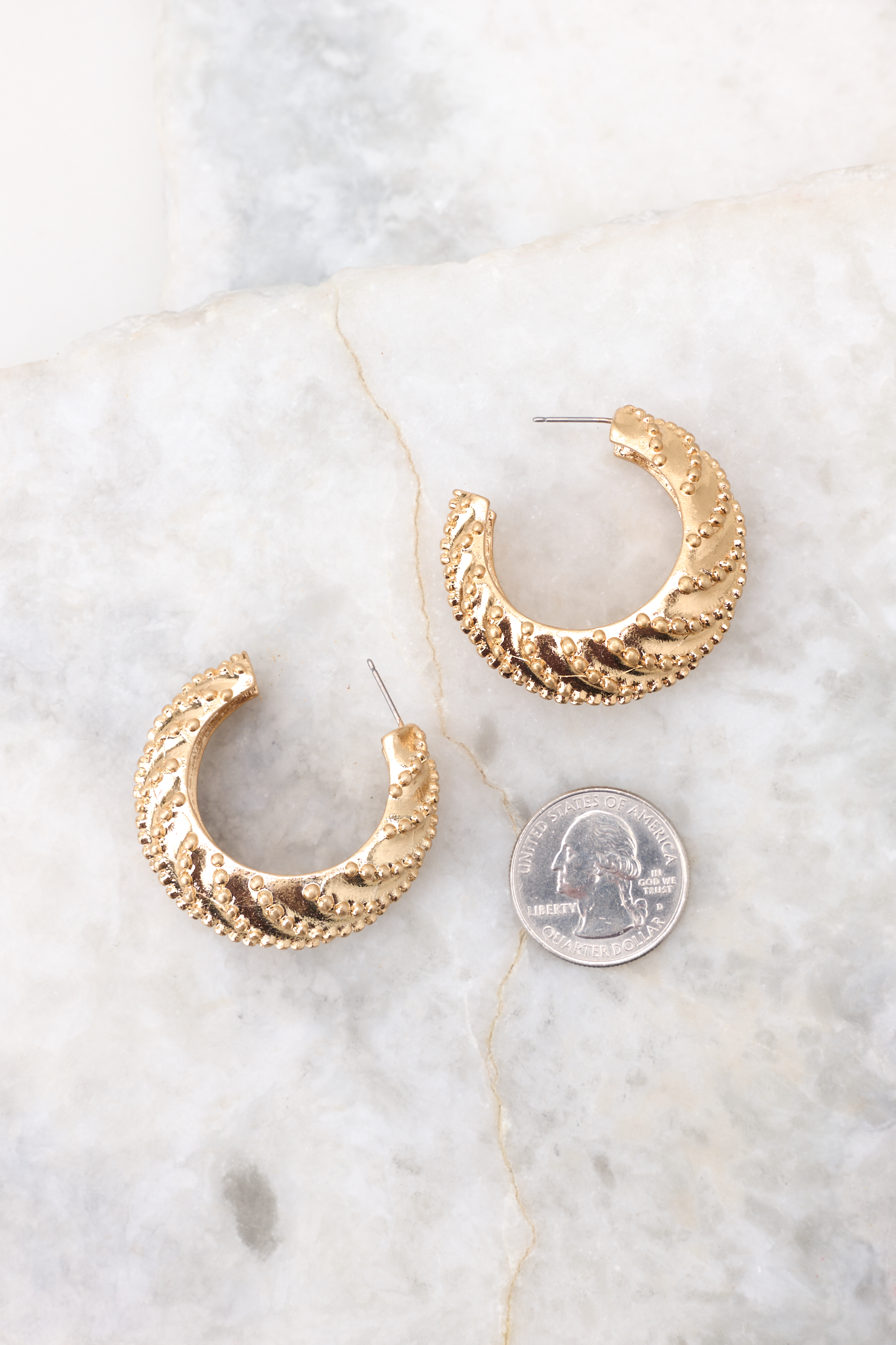 Gold studded hoop earrings compared to quarter for actual size. Earrings measure 1.5" in diameter.