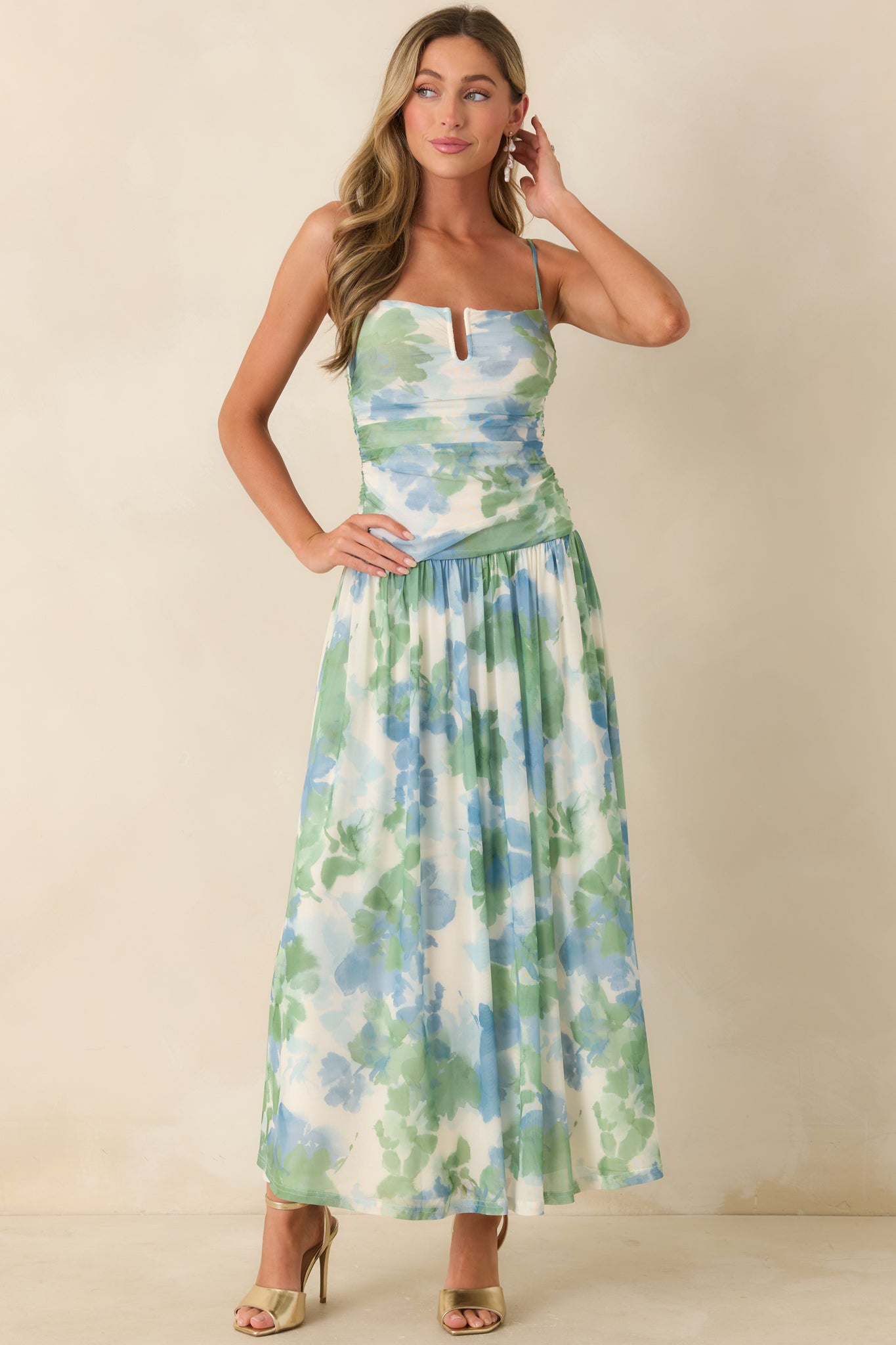 Flowing maxi dress with watercolor pattern, textured ruched bodice, and adjustable strap detail.