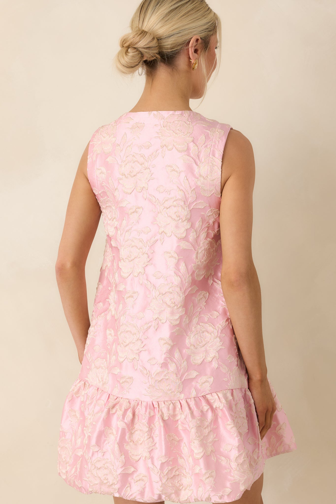 Rear view of sleeveless mini dress with textured floral fabric and gently tiered hemline.