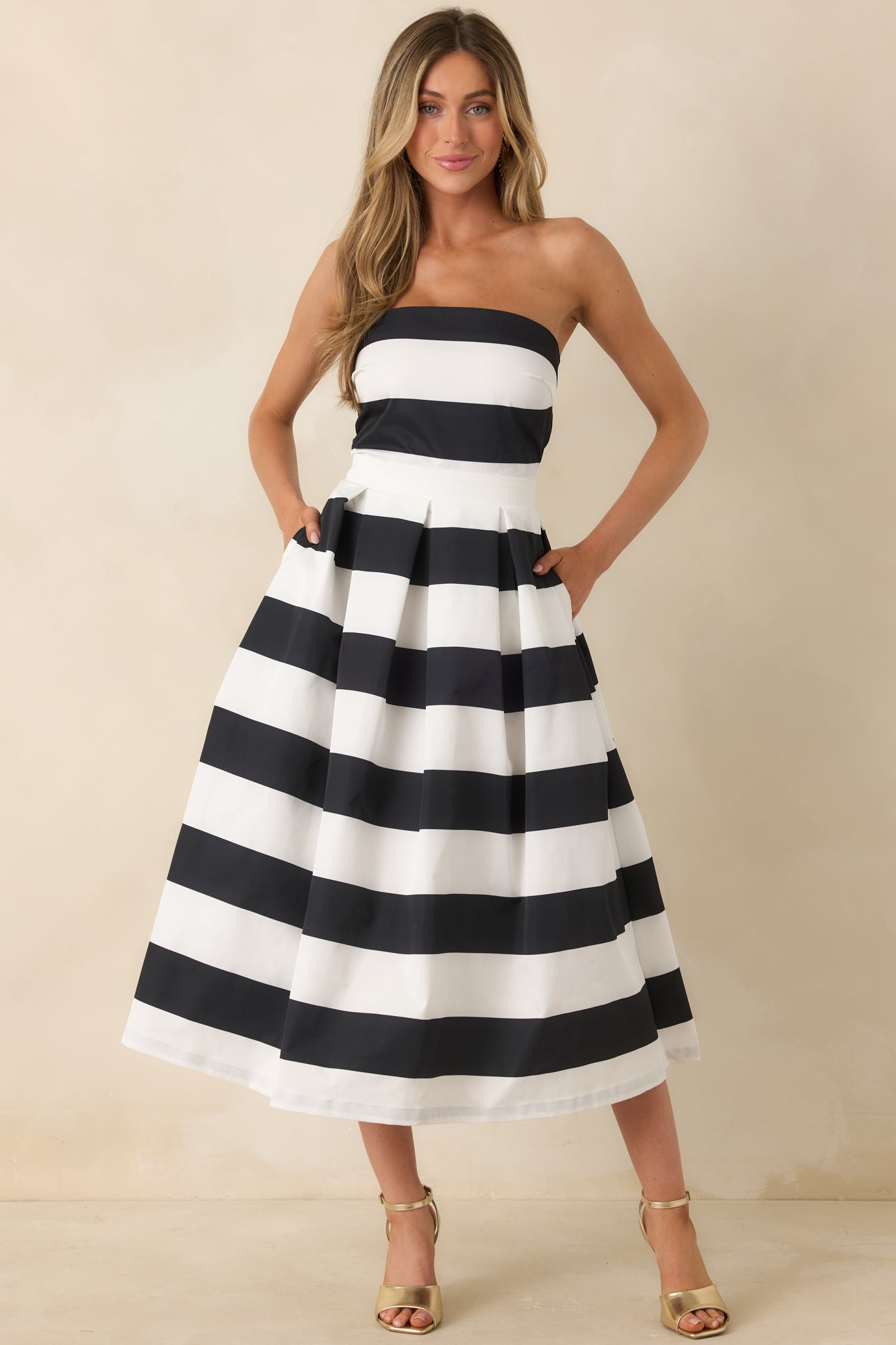 Front angled view of the dress featuring a strapless neckline, thick waistband, functional hip pockets, and a timeless stripe pattern.