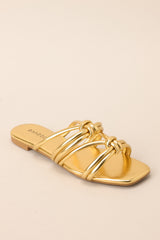 Angled side view of these gold sandals that feature gold knotted straps, and a slip on design.