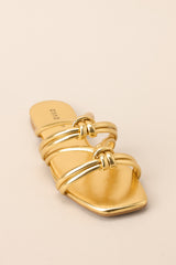Full side view of these gold sandals that feature gold knotted straps, and a slip on design.
