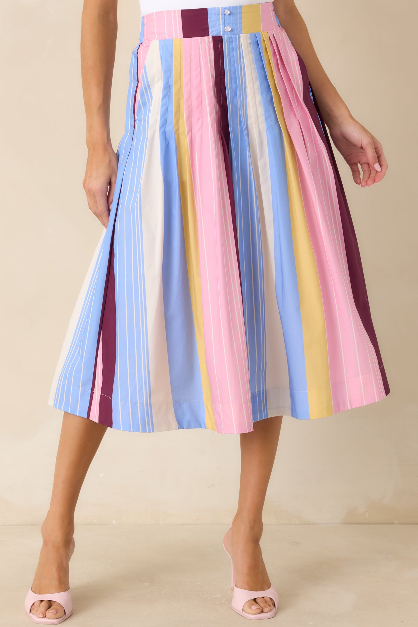 Flowing pleats on striped midi skirt showing movement and lightweight drape.