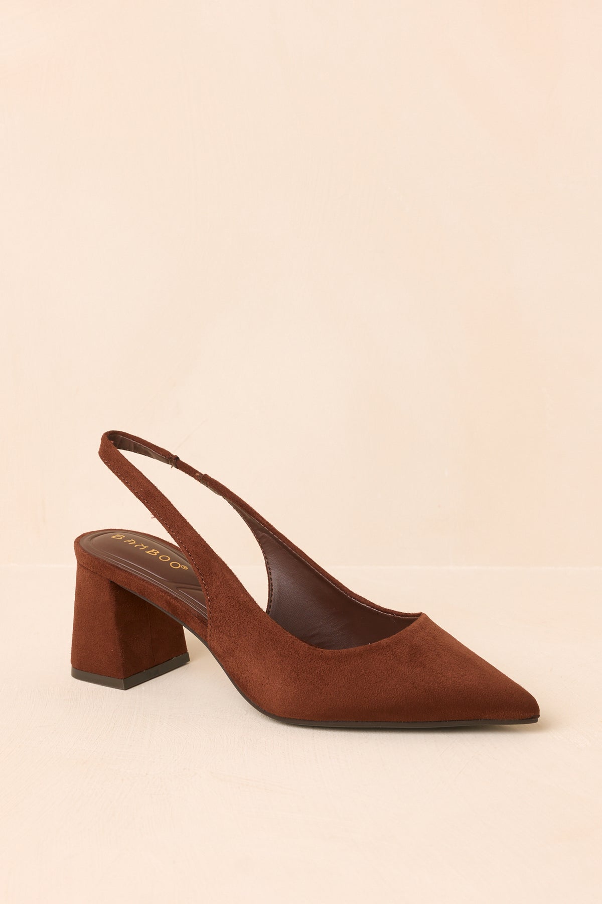 Brown pointed-toe heels displayed at an angled view, showcasing the slender slingback strap and open-back design.