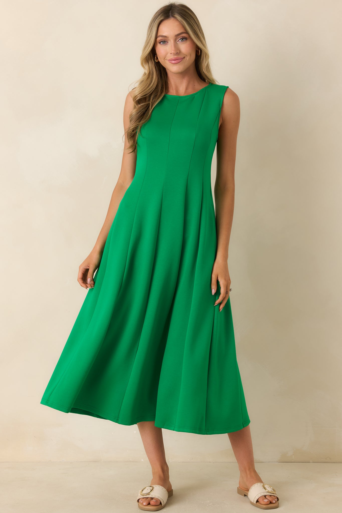 Green midi dress featuring a round neckline, sleeveless design, and a soft stretch fabric with a flowing draped silhouette.